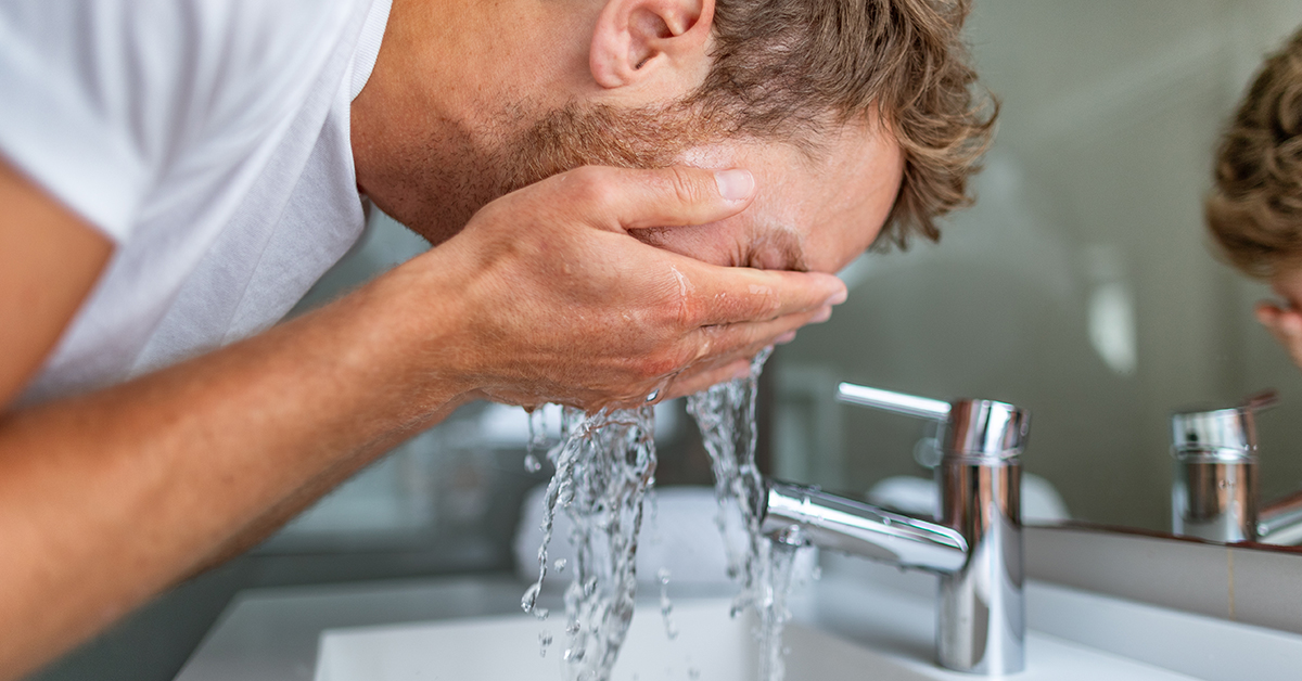 man washing face in sink