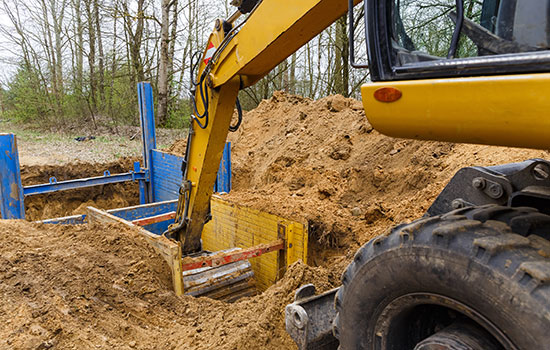 excavator digging out dirt in a trench box