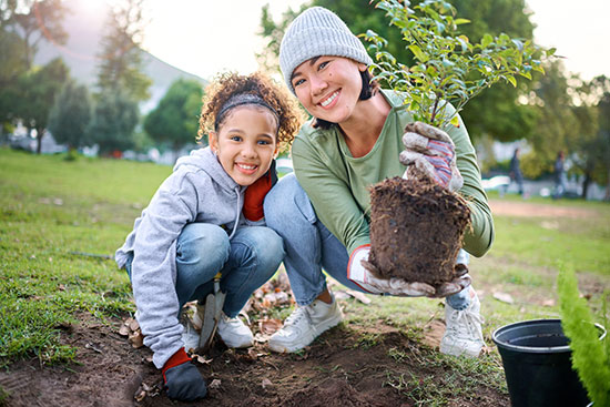 a smiling woman and child planting a tree