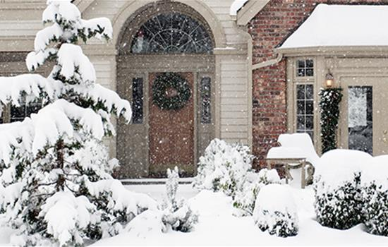 A closeup of the front of a home with active snowfall in the foreground.