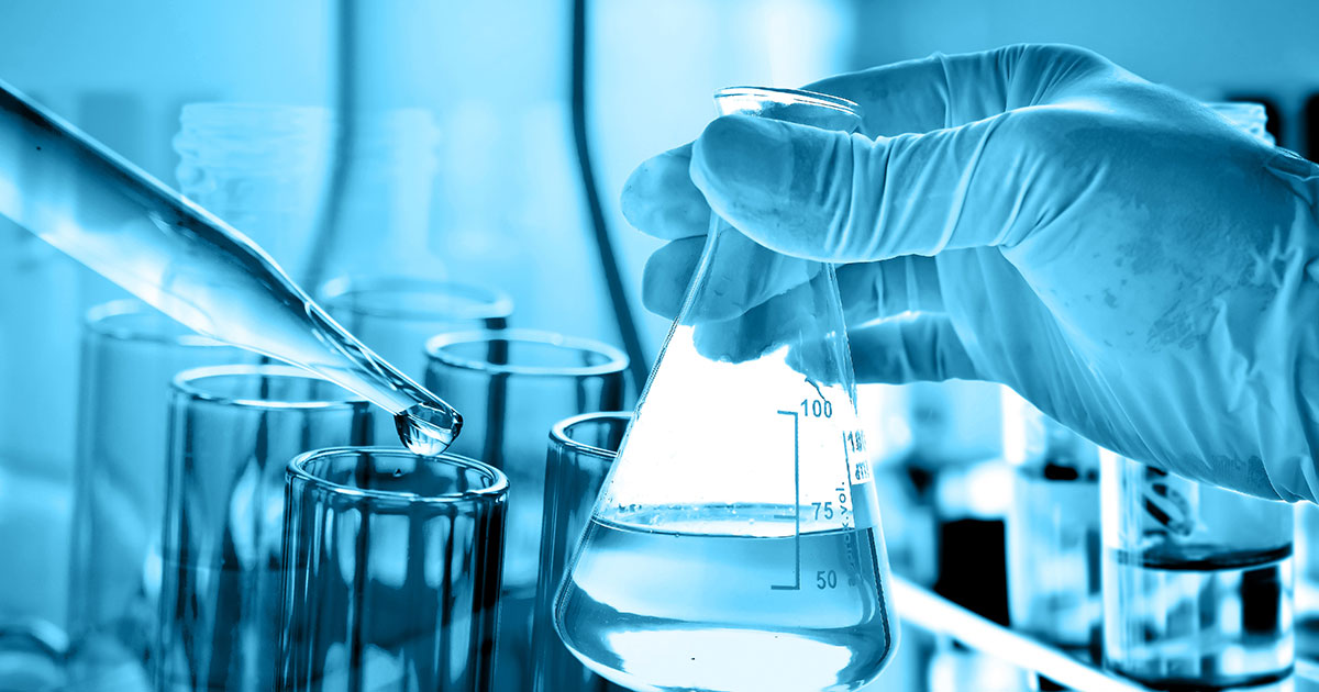 hand holding a flask with lab glassware in the background